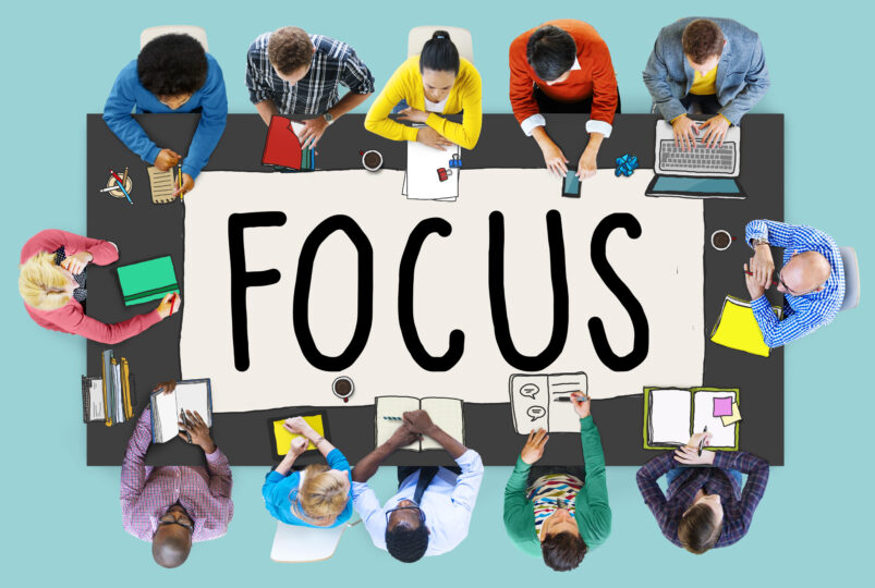 テーブルを囲んで１２名座っている。テーブルの上には、FOCUSと書かれた紙が置いてある。
