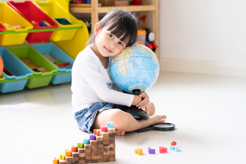 かわいい外国人の女の子が地球儀を抱えて座っている。