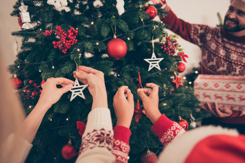 家族でクリスマスツリーの飾り付けをしている写真
