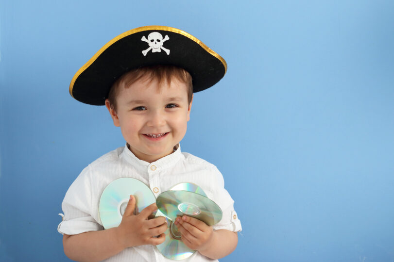 帽子をかぶった3歳くらいの男の子が数枚のDVDを持って微笑んでいる。