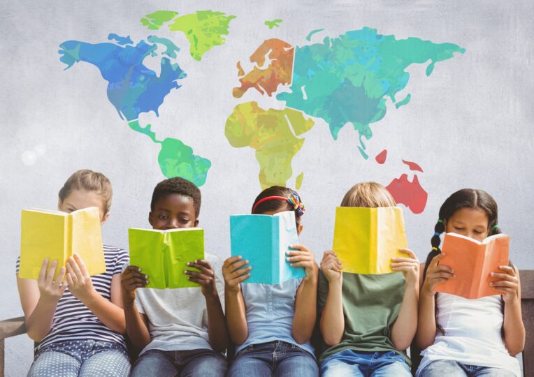 5人の国籍の異なる子どもたちが世界地図の絵の前に座っている。