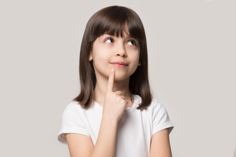 女の子が人差し指を口元にもっていき、考える表情をしている。