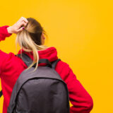 大学生の女性が頭をかきながら困っている様子の後ろ姿
