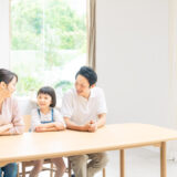 父親、母親、女の子の家族がリビングでくつろいでいる。