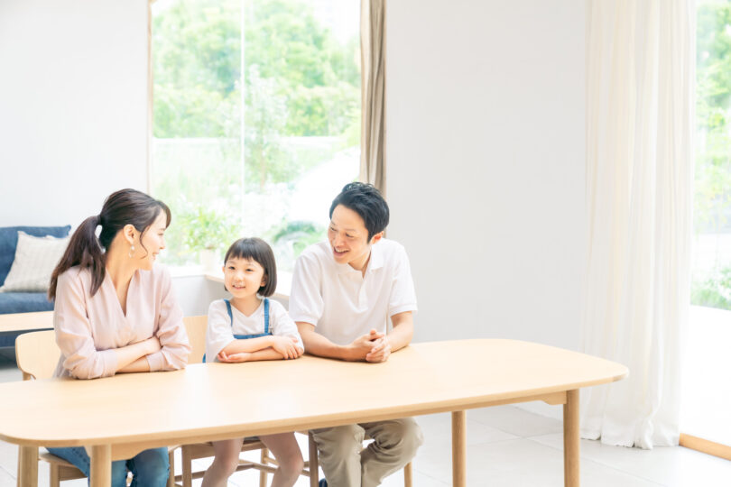 父親、母親、女の子の家族がリビングでくつろいでいる。