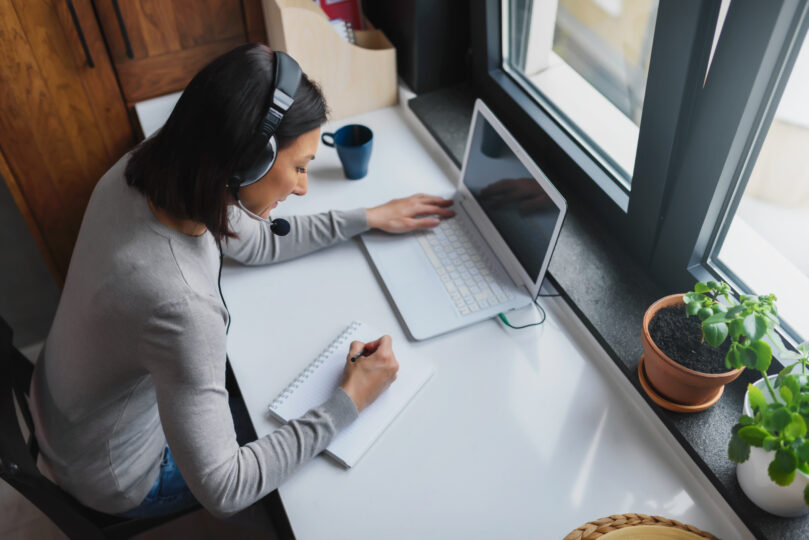 若い女性がラップトップを開いて勉強している。