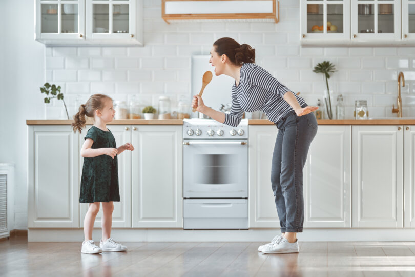 母親と女の子がキッチンで一緒に歌っている。