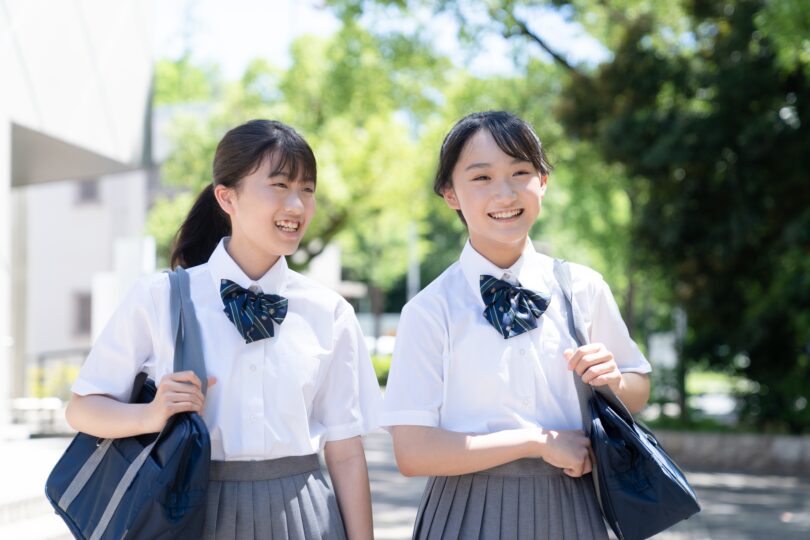 女子学生二人が並んで外を歩いている。