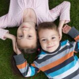 7歳の女の子と3歳の男の子が芝生に寝そべっている。