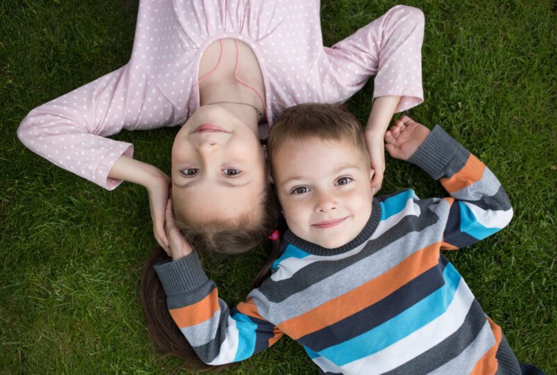 7歳の女の子と3歳の男の子が芝生に寝そべっている。