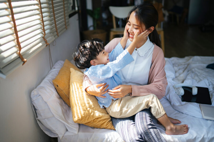 男の子が母親の膝に載って微笑んでいる
