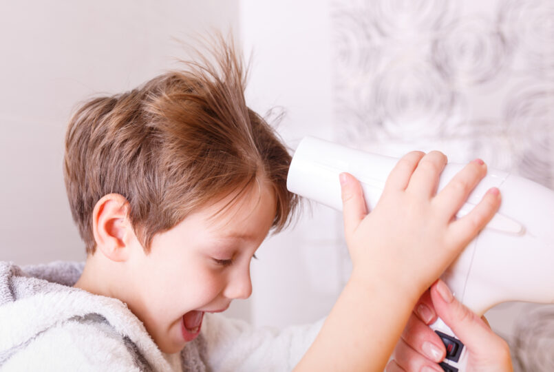 母親にヘアブローをしてもらい、嬉しそうにしている少年