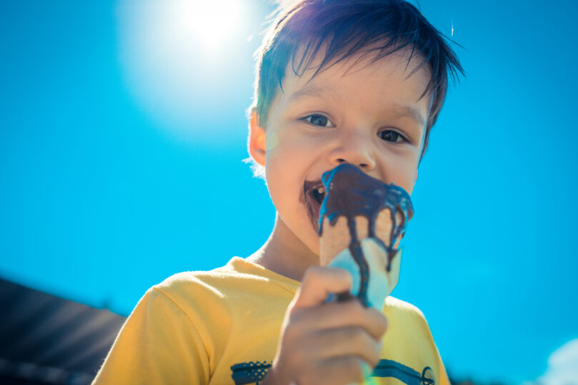 チョコレートアイスクリームを頬張る3歳くらいの男の子